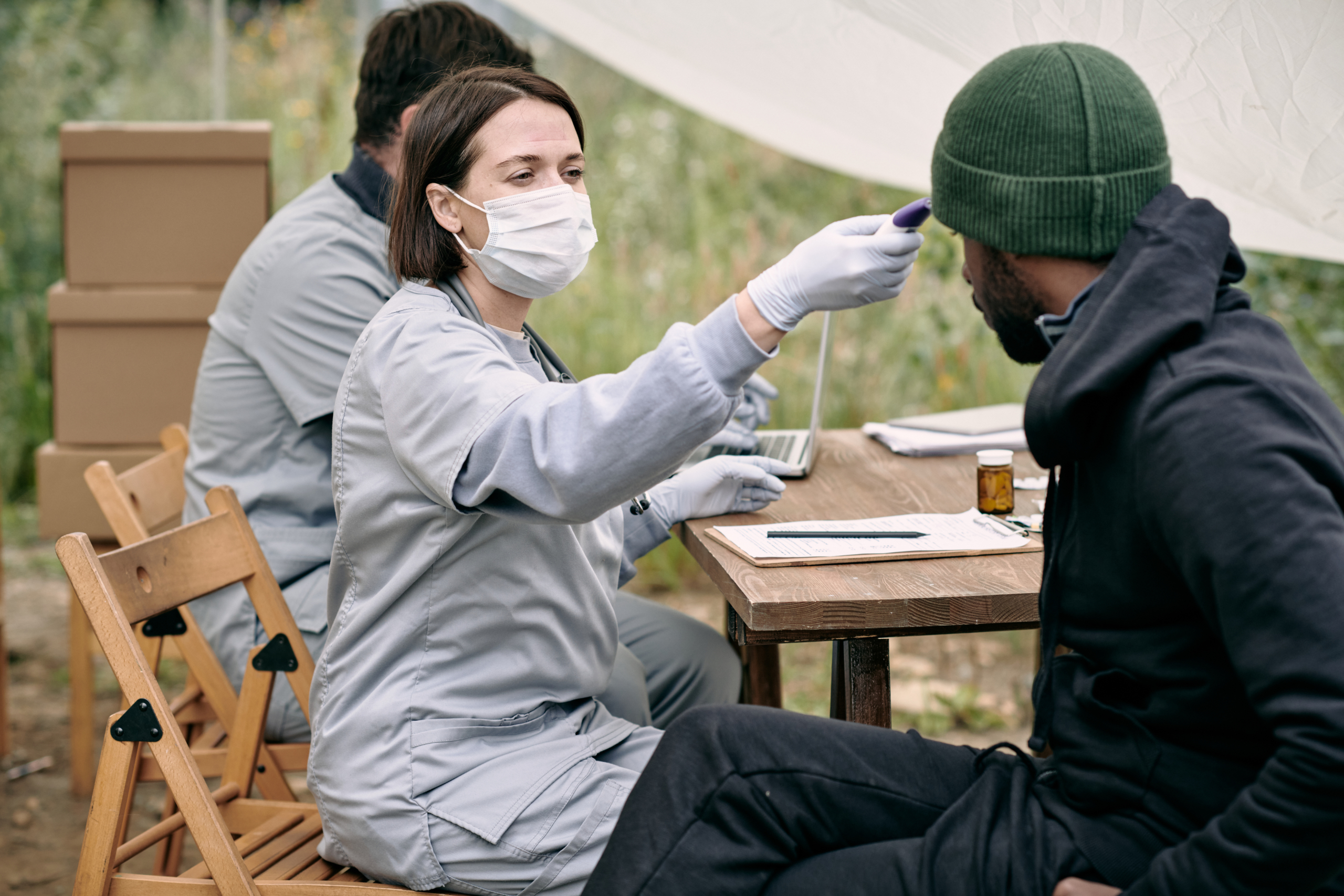 Doctor in protective mask measuring body temperature of sick man Arbeitsmedizinische Vorsorge