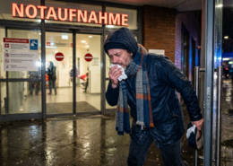 Mann mit Taschentuch in Notaufnahme, um Krankschreibung zu erhalten